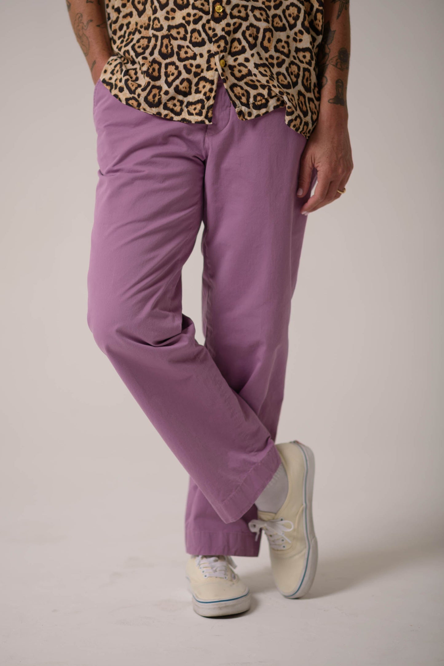Person wearing a leopard print top and purple pants on a plain background