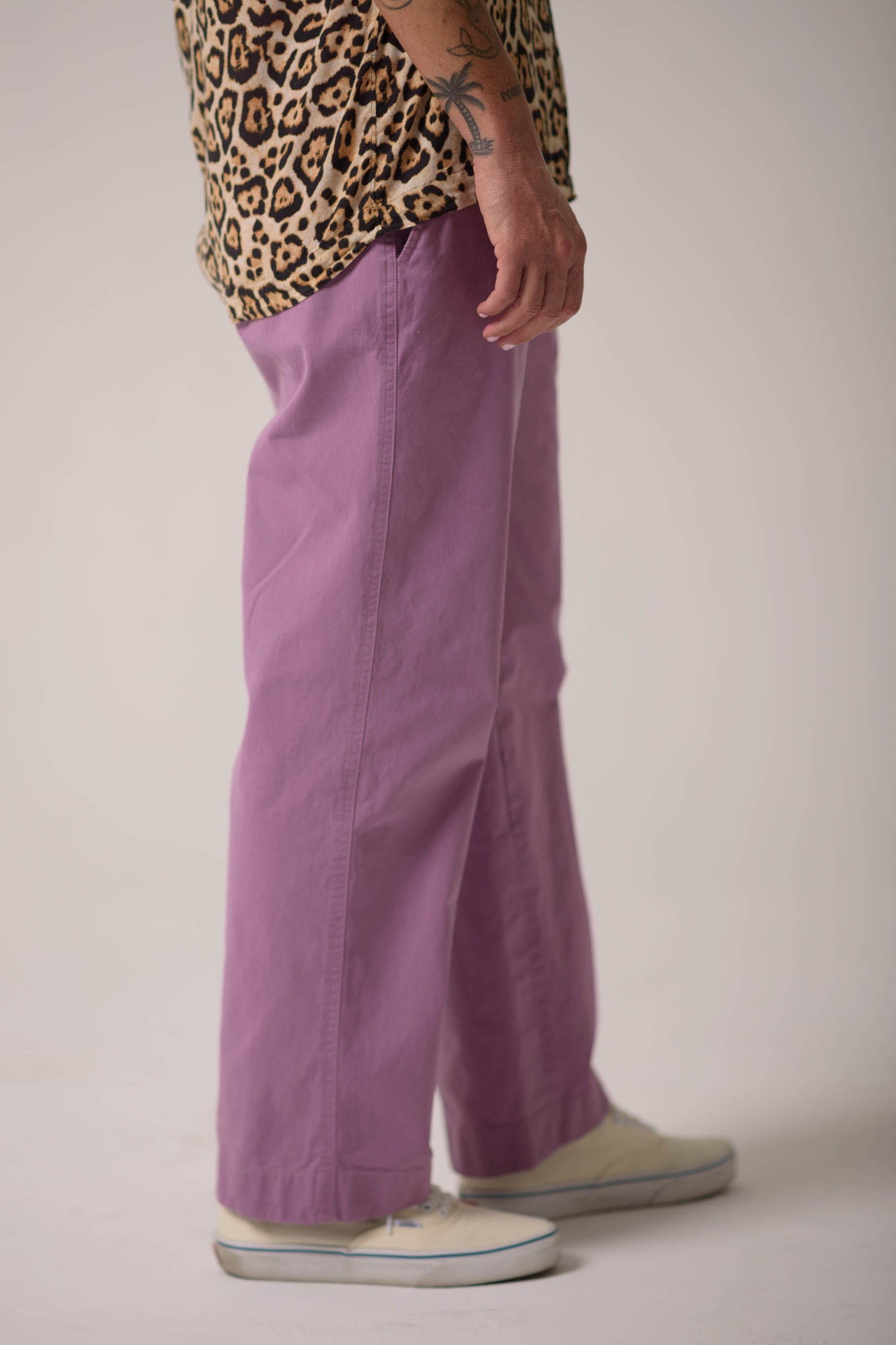 Person wearing purple pants and a leopard print top on a plain background