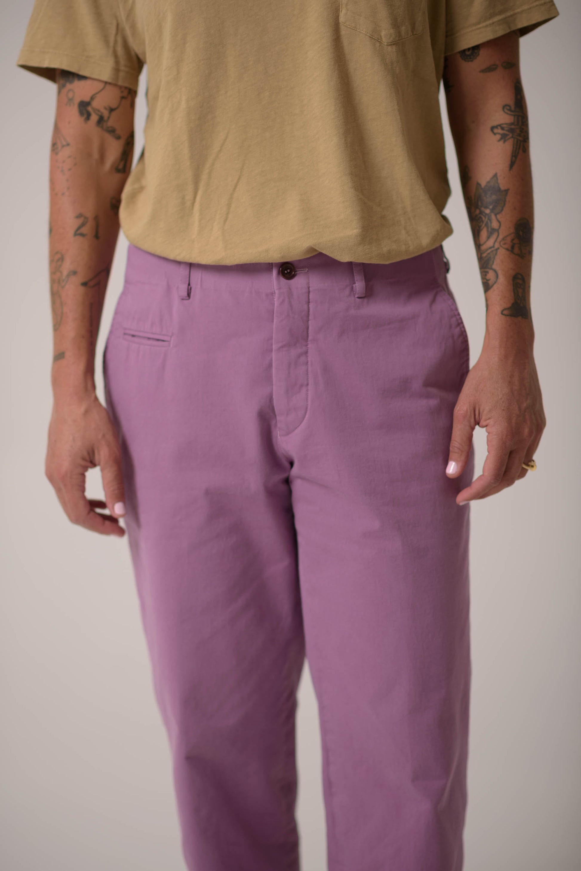 Person wearing a mustard yellow shirt and purple pants on a plain background